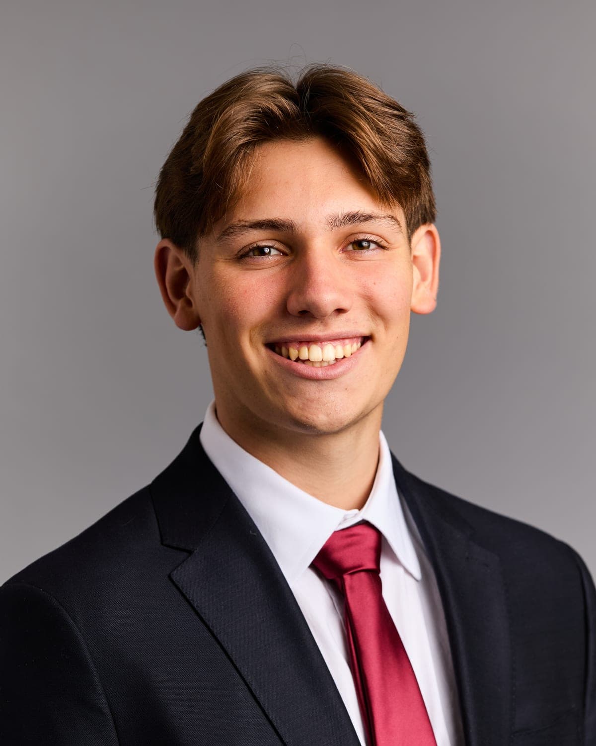 Portrait of Ben Llados smiling in a navy suit and burgundy tie