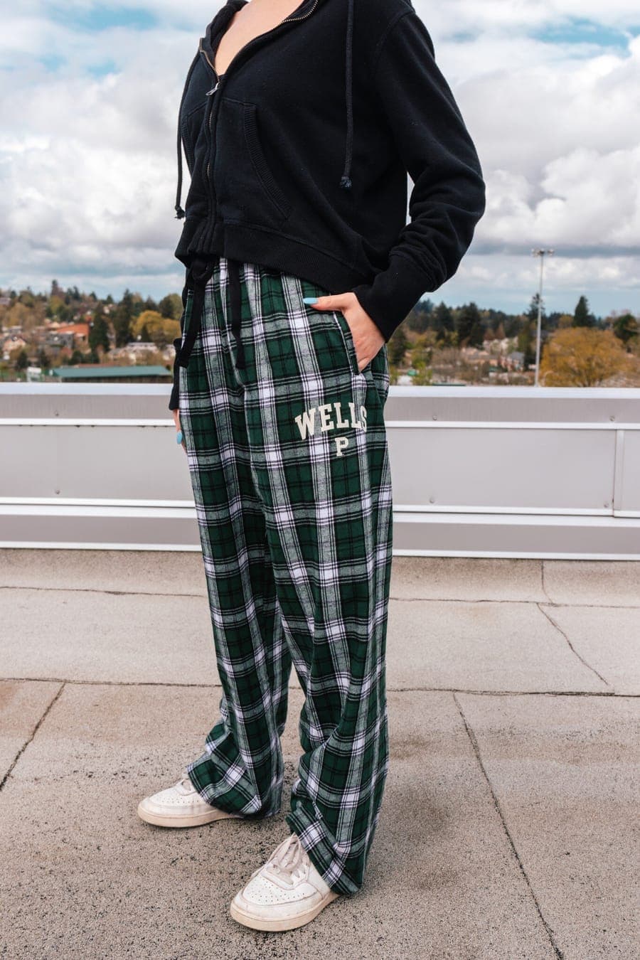 Student standing on the rooftop in the green plaid Wells flannel pants